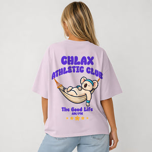 A woman shown from the back wearing an oversized light lavender t-shirt with a colorful graphic of a cartoon koala in a hammock and the text 'CHLAX ATHLETIC CLUB'.