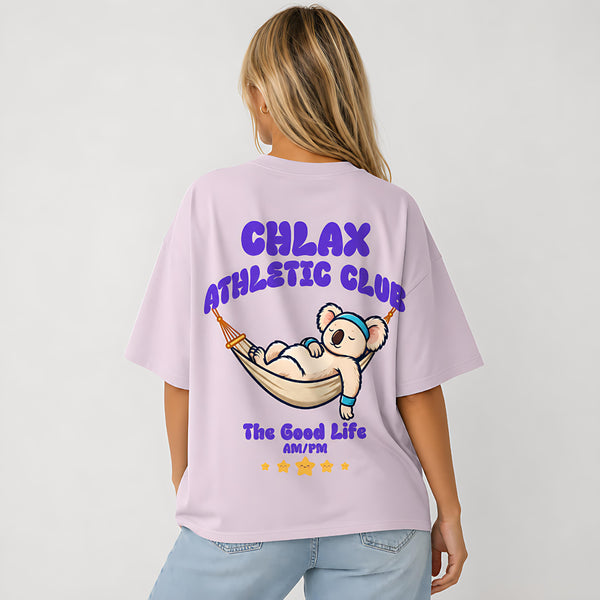 A woman shown from the back wearing an oversized light lavender t-shirt with a colorful graphic of a cartoon koala in a hammock and the text 'CHLAX ATHLETIC CLUB'.