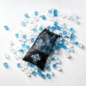 Blue and clear CHLAX reusable ice cubes scattered around a black mesh drawstring bag with the CHLAX logo, on a white background.