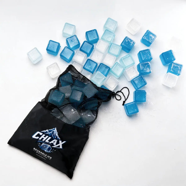 Blue and clear reusable ice cubes scattered on a white surface next to a black mesh drawstring bag printed with the CHLAX logo.