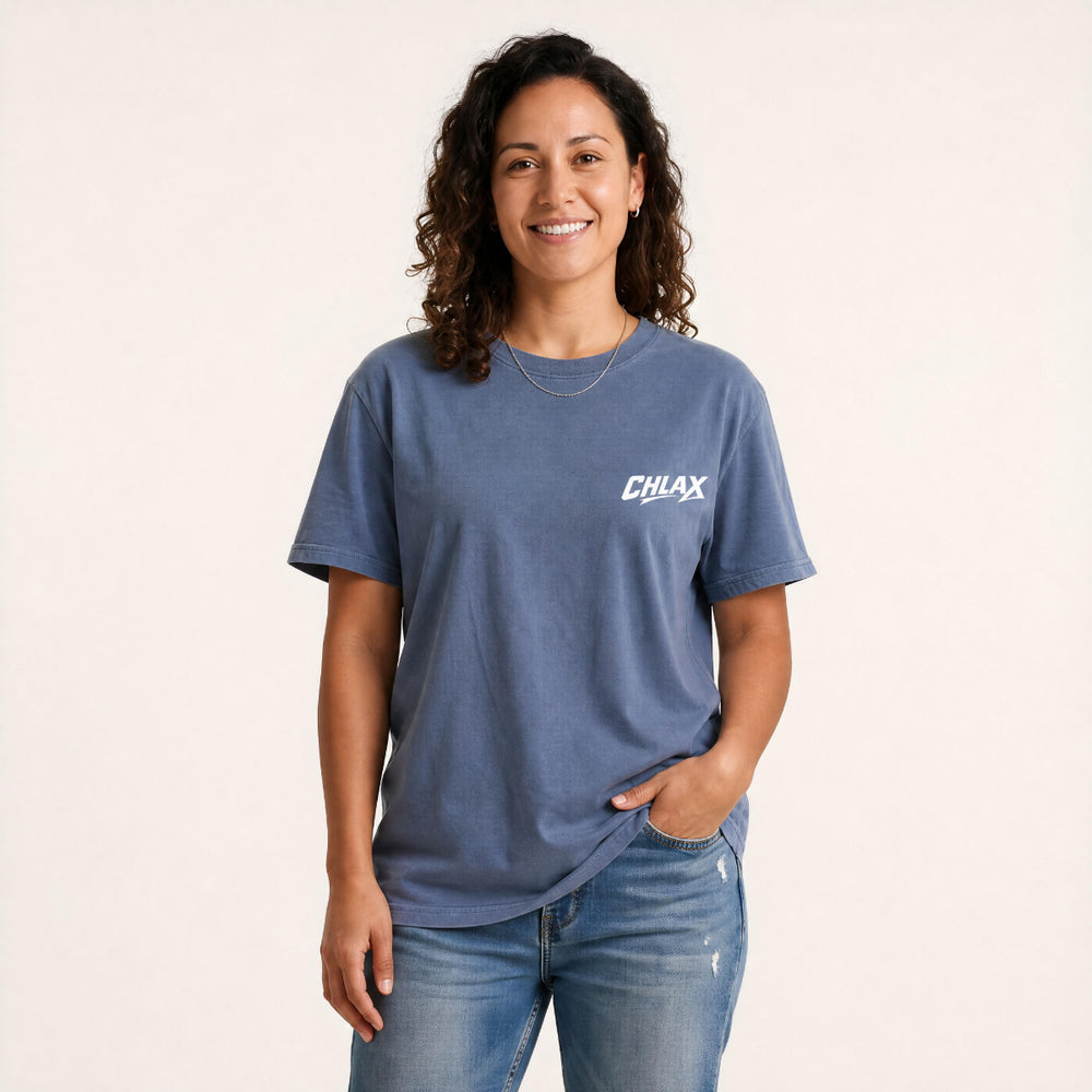 A woman wearing a blue crewneck t-shirt with a white 'CHLAX' logo on the left chest, paired with blue jeans, standing against a plain off-white background.