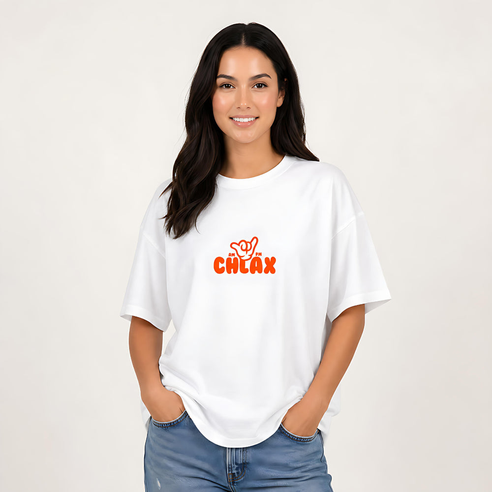 A woman with long dark hair wearing a white oversized t-shirt with a red 'CHLAX' graphic on the chest, paired with blue jeans, standing against a plain off-white background.