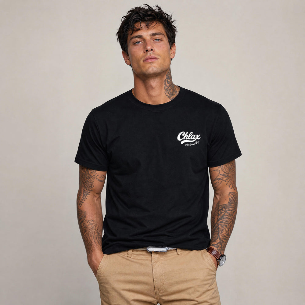 A man wearing a black crewneck t-shirt with a white 'Chlax' logo on the left chest, paired with khaki pants, standing against a neutral beige background.
