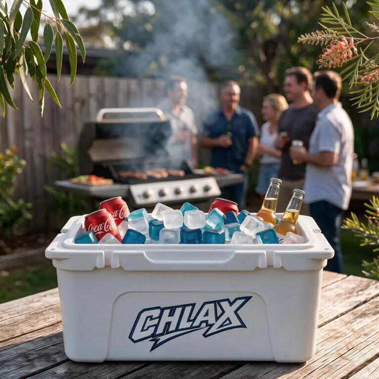 A white CHLAX cooler filled with ice and beverages sits on a wooden table in a backyard, with a grill and people visible in the blurred background.