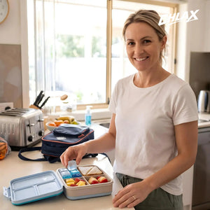 A woman in her home kitchen packing a lunch box with fresh food and CHLAX reusable ice cubes.