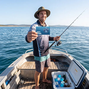 A man standing on the deck of a small boat on the water holds up a blue gift card toward the camera. The card has the PHOEN logo and reads 'GIFT CARD'.