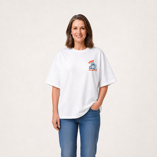 A woman shown from the back wearing a white graphic t-shirt with a cartoon character and orange text that reads 'CHLAX. THE GOOD LIFE.