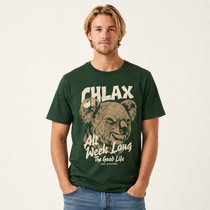 A man wearing a dark green graphic t-shirt with a koala illustration and the text 'CHLAX All Week Long The Good Life' by Chill Outfitters, paired with blue jeans against a light off-white background.