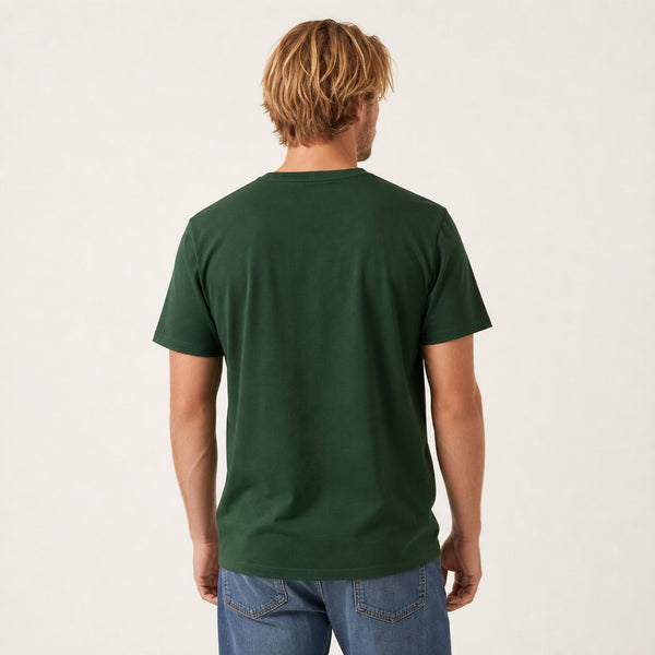 A man viewed from behind wearing a dark green short-sleeve crewneck t-shirt and blue jeans, standing against a plain off-white studio background.
