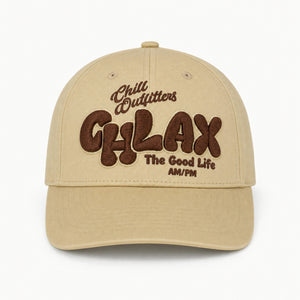 A beige baseball cap with brown embroidered text reading 'Chill Outfitters CHLAX The Good Life AM/PM' on the front, shown against a plain white background.