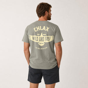 A man wearing a sage green t-shirt with a large cream graphic on the back, shown from behind against a light gray studio background.