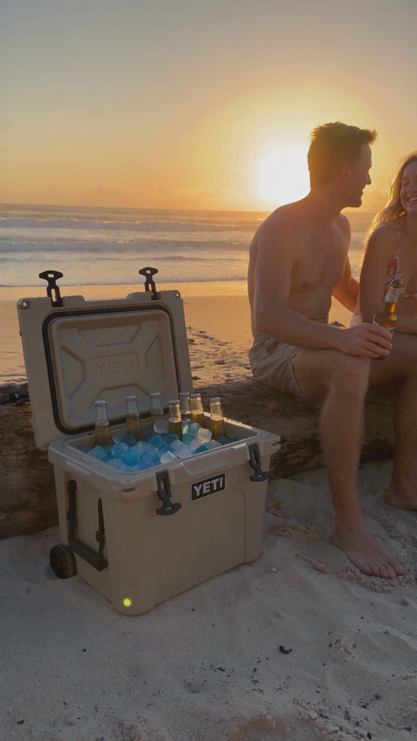 Australian beach at dusk with a Yeti cooler full of beer & CHLAX reusable ice cubes showing a young couple sitting on a log drinking beer. Reel format.